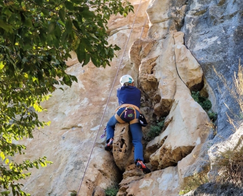 rrampicata guidata in Umbria: sportivo affronta una parete rocciosa con supporto tecnico.